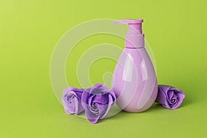 Cosmetic product in a purple bottle and purple roses on a green background