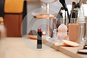 Cosmetic products and makeup accessories on dressing table.