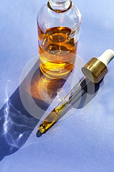 Cosmetic serum glass bottle on violet very peri background. Beauty skincare facial treatment, glass facial dropper pipette