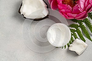 Cosmetic skin care, coconut face cream and pink peony flower on brigt background.