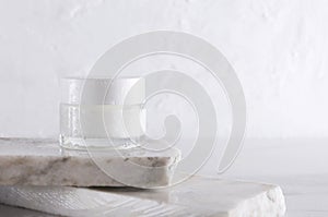 Cosmetic skincare jar on the pieces of white marble against white wall.Empty space for design
