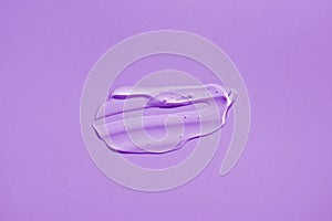 Cosmetic smear. Appearance of the texture of the transparent gel on purple background.