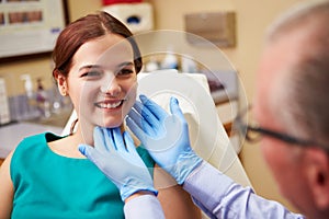 Cosmetic Surgeon Examining Female Client In Office