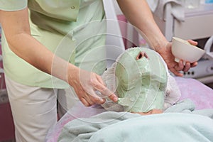 Cosmetician applying alginate facial mask.