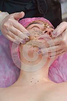 Cosmetician applying coral face peel.