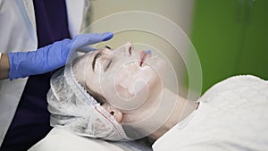 Cosmetician applying cream to woman s face