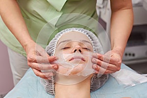 Cosmetician applying facial collagen mask.