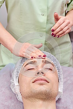 Cosmetician applying facial cream.