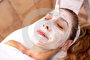 Cosmetician applying a facial layer beauty mask