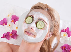 Cosmetician applying facial mask on face of woman