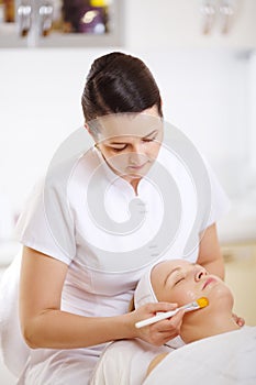 Cosmetician applying a facial mask using brush