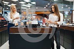 Cosmetician at counter and woman, cosmetics store