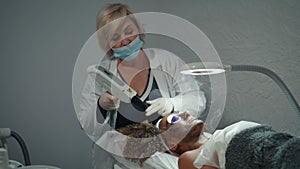 Cosmetician doing peeling procedure in beauty salon. Doctor examine face skin