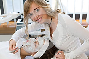 Cosmetician giving client facial skincare mask