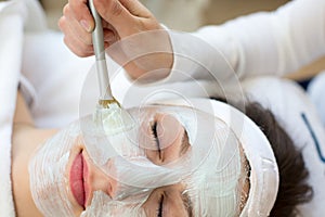 Cosmetician giving client facial skincare mask
