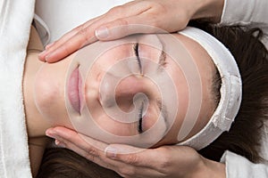 Cosmetician giving customer face massage photo