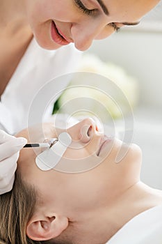 Cosmetician giving eyelash treatment to customer