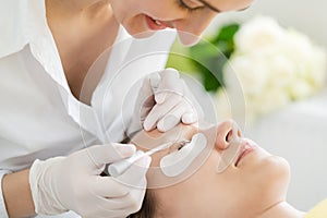 Cosmetician giving eyelash treatment to customer