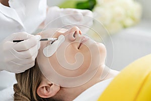 Cosmetician giving eyelash treatment to customer