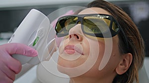 Cosmetician making laser procedure to woman client in beauty salon close up.