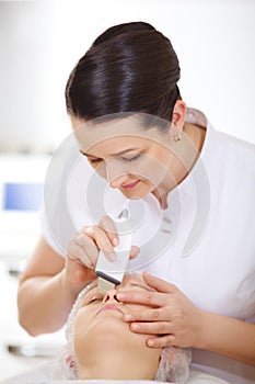 Cosmetician making ultrasonic face cleaning