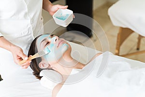 Cosmetician Pampering Young Woman Lying On Bed