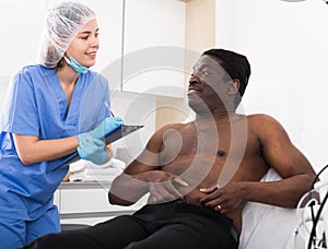 Cosmetician with papers talking to man before procedure in clinic