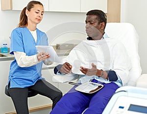 Cosmetician with papers talking to man before procedure in medical esthetic office
