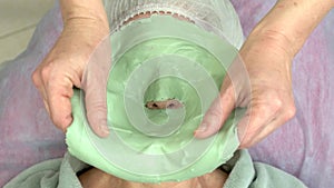 Cosmetician removing facial mask.