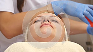 Cosmetician removing mask from client face at beauty salon. Top view