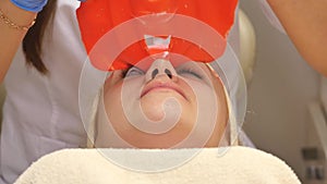 Cosmetician removing mask from client face at beauty salon. Top view