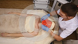 Cosmetician removing mask from client face at beauty salon. Top view