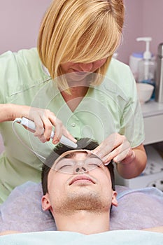 Cosmetician with ultrasonic face scrubber.