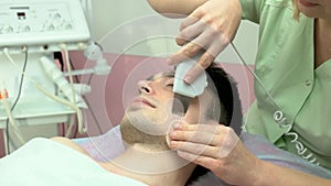 Cosmetician with ultrasonic face scrubber.