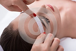 Cosmetician undergoing waxing procedure for human brow