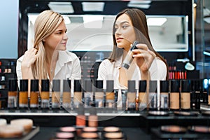 Cosmetician and woman choosing nail varnish