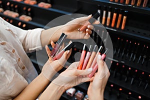 Cosmetician and woman holds nail varnish in store