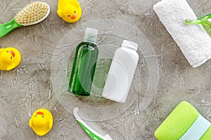 Cosmetics for baby bath, towel and toys on gray background top view