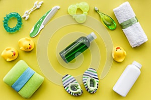 Cosmetics for baby bath, towel and toys on yellow background top view pattern