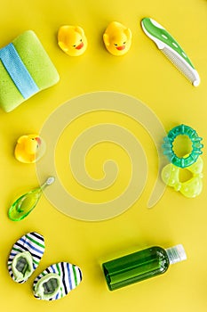 Cosmetics for baby bath, towel and toys on yellow background top view space for text