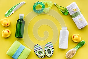 Cosmetics for baby bath, towel and toys on yellow background top view space for text