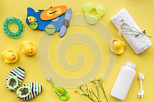Cosmetics for baby bath, towel and toys on yellow background top view space for text