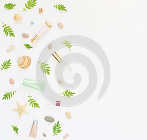 Cosmetics background. Cosmetics SPA makeup tubes, bottles, sea pebbles and shells on white background. Flat lay, top view.