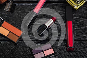 Cosmetics on a black, nail polish, eye shadow palette, lipstick, brush, parfume