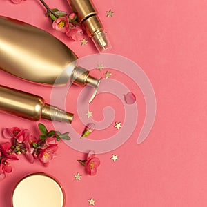 Cosmetics Branding Concept. Cosmetics, spring pink flowers, gold stars confetti on pink background. Cosmetic mock up gold bottles