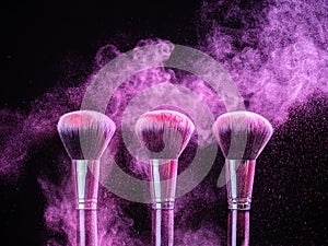 Cosmetics brush and explosion colorful makeup powder background - beauty make-up product and mineral cosmetic concept