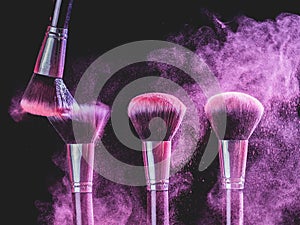 Cosmetics brush and explosion colorful makeup powder background - beauty make-up product and mineral cosmetic concept