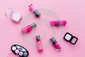Cosmetics on colorful background. Bright pink nail polish, lipstick, eyeshadows on pink background top view