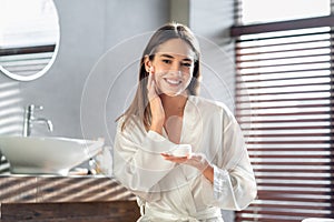 Cosmetics Concept. Young Beautiful Lady Applying Moisturising Cream And Smiling At Camera