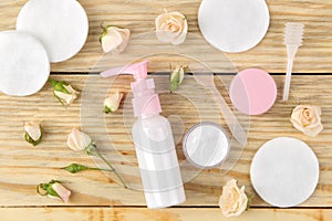 Cosmetics for face and body. Cream in pink bottles with fresh roses on a natural wooden background. creams and lotion. spa. top vi